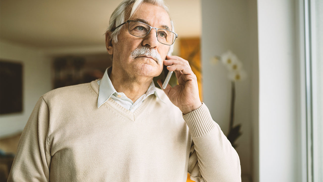 Oudere man met een male slingsysteem praat aan de telefoon.