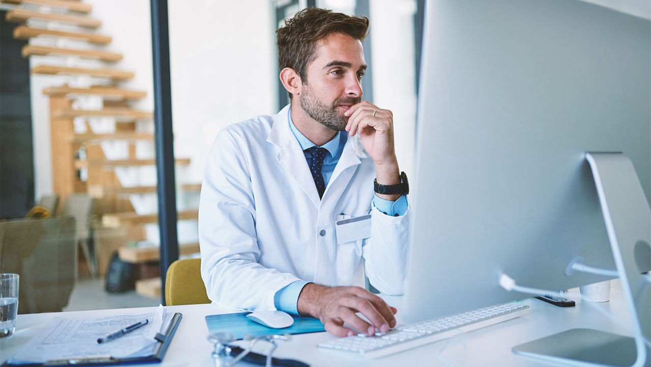Dokter leest onderzoek over laserbehandeling op zijn computer.