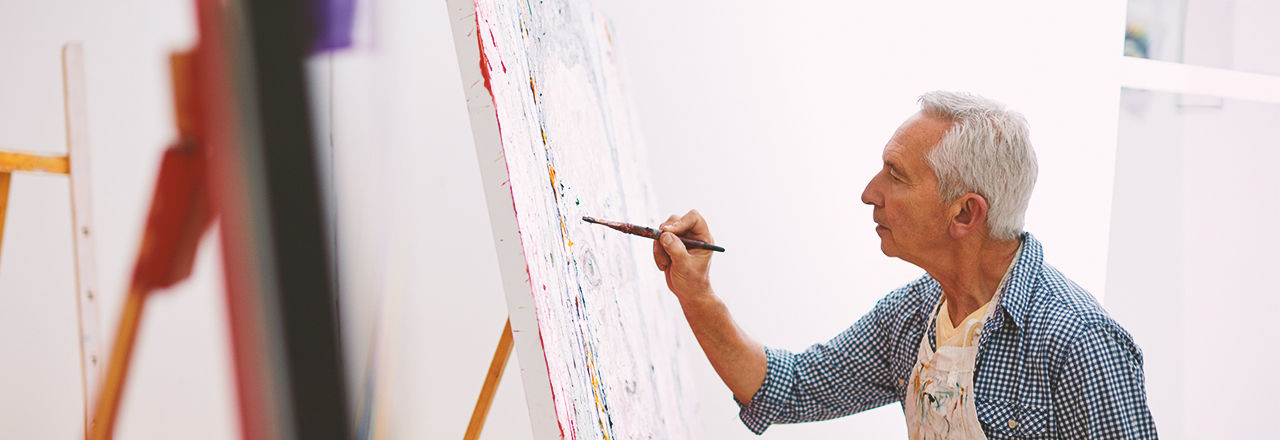 Man som återhämtar sig efter laserbehandling och målar en tavla.