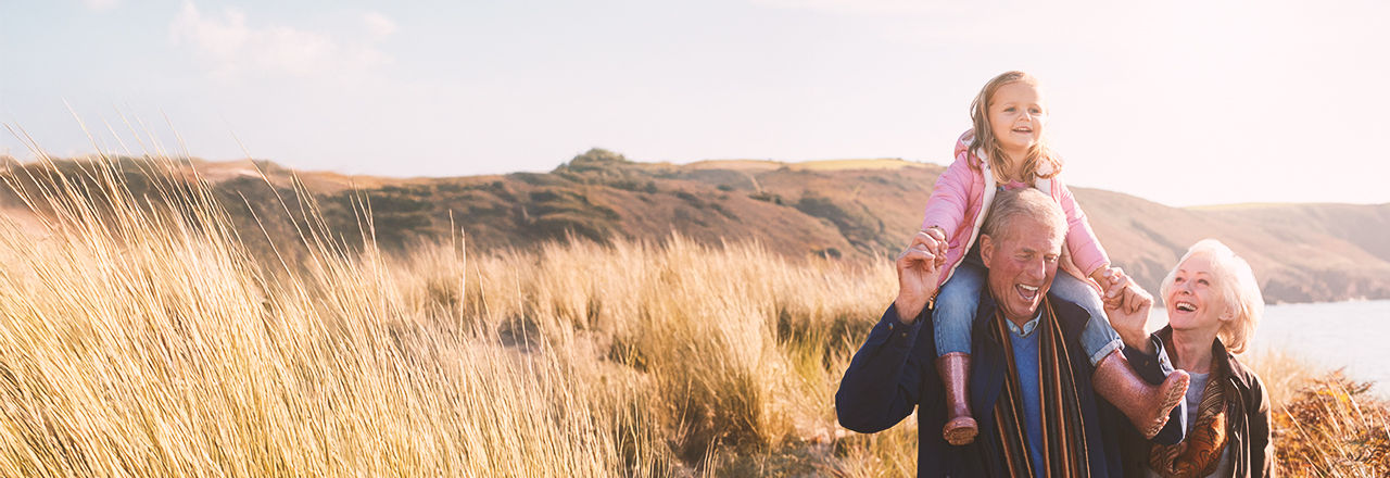 Äldre par med sitt barnbarn på en äng – morfadern lider av prostatacancer.